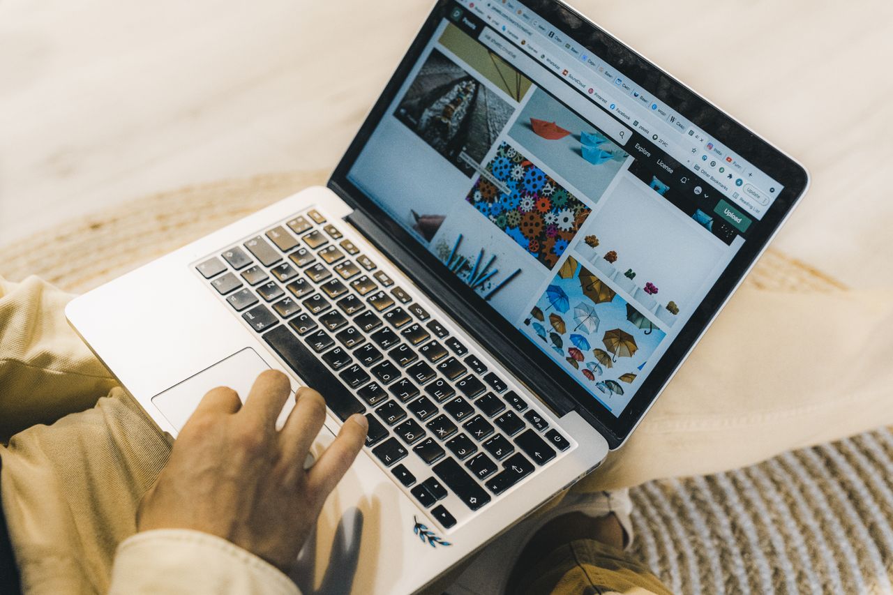 Une personne utilise un ordinateur portable pour parcourir des sites de photos libres de droits. Travail en freelance dans un cadre chaleureux.