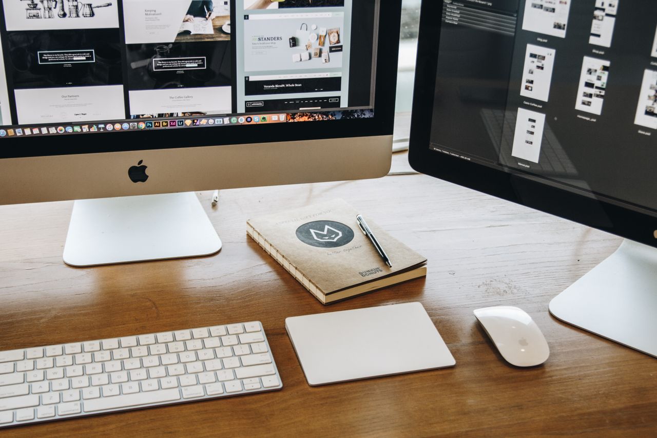 An understated desk arrangement with two monitors, a keyboard, mouse, and notebook, created for productive work.
